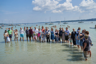 Seetaufe am Ammersee - festlich gekleidete Menschen stehen im Wasser